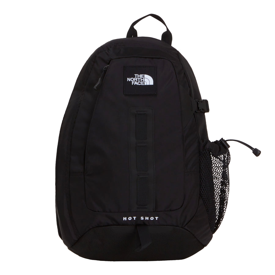 A black The North Face Hot Shot Sling Bag featuring HOT SHOT printed at the bottom, a top handle, front webbing, side mesh pocket, and the brand logo displayed near the top—this versatile design seamlessly blends classic style with practical functionality.