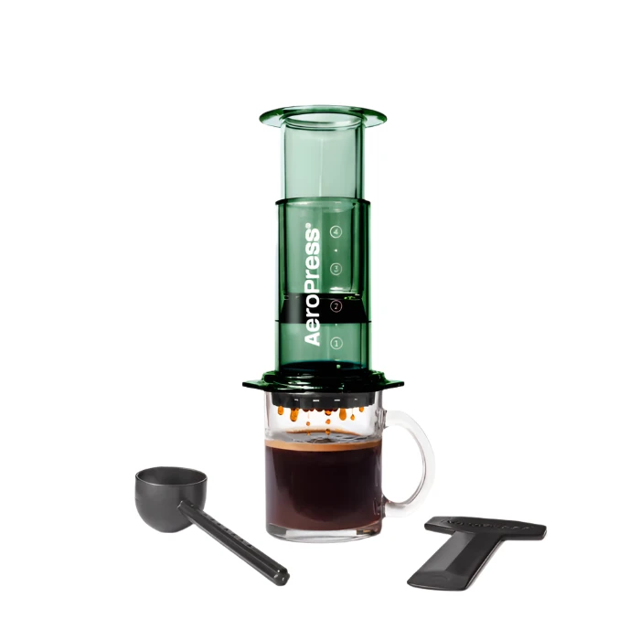 Aeropress coffee maker with a glass of brewed coffee on a white background