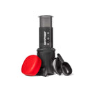 AeroPress coffee maker with a red lid and black scoop on a white background