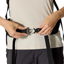 A person wearing a light beige shirt and dark pants fastens a black plastic buckle on the Rab Airox ND22L Day Pack’s strap around their waist with both hands, showcasing the comfort of the ventilated AEROFIT back system designed specifically for women’s hiking backpacks.