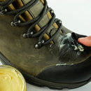 Person applying waterproof wax to a green boot with a jar of cream next to it