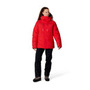A person wearing the Rab Batura Jacket—a bright red, waterproof down jacket filled with 800FP European goose down—alongside black pants and hiking boots, stands facing slightly to the right against a plain white background, ready for high-altitude expeditions.