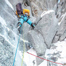 Person ice climbing on a frozen mountain with ropes and gear.