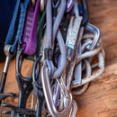 Collection of climbing equipment including carabiners and ropes on a wooden surface