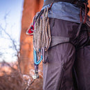 Person wearing climbing gear with ropes and carabiners against a natural rock background