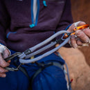 Person holding climbing equipment with a focus on carabiners and rope.