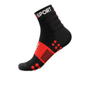 The Compressport Unisex Training Socks (2 Pack) are black running socks with red accents, grip dots on the sole, arch support, and SPORT in white at the top. Breathable and shown against a white background.