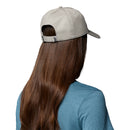 Person with long brown hair is seen from behind, wearing a blue shirt and the Columbia Provisions Ball Cap—a light gray cotton cap with an adjustable back closure—worn backwards, set against a plain white background.