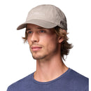 A man with light brown hair and a short beard wears a Columbia Provisions Ball Cap—a cotton baseball cap with an adjustable back closure—in light gray, along with a blue shirt, as he looks slightly to the side against a white background.