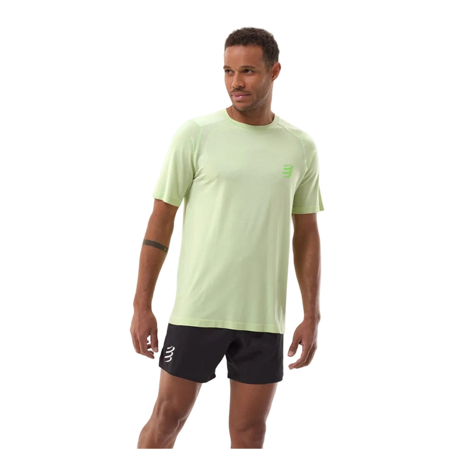 Man wearing a light green t-shirt and black shorts on a white background