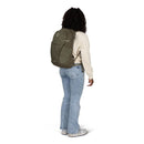 A person wearing a sage green Osprey Daylite Plus backpack with side mesh pockets.