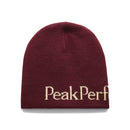 A maroon PP Hat by Peak Performance, made from 100% acrylic, features a double-layer knit for added warmth and displays the partial PeakPerf text in beige along the bottom.