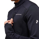 A person wearing the Peak Performance Mens Trail Polartec Power Grid Half Zip Fleece—a black, textured technical midlayer made from Polartec Power Grid fabric with a zippered chest pocket and brand logo visible on the chest—partially shown from the neck to the upper torso.