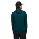 A person is seen from behind against a plain white background, wearing the Peak Performance Mens Trail Polartec Power Grid Zip Hooded Fleece in dark green, paired with black pants and a black cap.