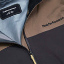 Close-up of the Peak Performance Mens Vislight GORE-TEX C-Knit 3L Shell Jacket, featuring the brands logo on the chest and an interior label. This lightweight, waterproof jacket showcases a color-block design in brown, black, and gray with a visible zipper.