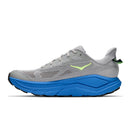 The Hoka Mens Challenger 8 Trail Running Shoe is pictured in a side profile view on a white background, featuring a gray mesh upper, neon green Hoka logo, blue cushioned sole, black outsole for reliable traction, and a green pull tab at the heel—designed as an all-terrain running shoe that provides comfort and stability for trail runners.