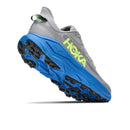 The Mens Challenger 8 Trail Running Shoe by Hoka is shown in gray with a vibrant blue sole and yellow logo, captured from a low rear angle that highlights its rugged tread pattern and thick, cushioned sole—perfect for trail runners looking for all-terrain performance.