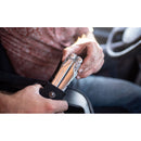 While sitting in a vehicle, a person removes a Leatherman Surge Multitool from a black pouch, with their hands and part of the steering wheel visible.