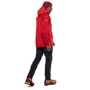 A person wearing a red Mountain Equipment Mens Lhotse GTX Pro Jacket, black pants, orange and black hiking shoes, and a red beanie stands in profile facing left against a white background.