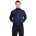 A person stands facing forward, wearing the Mountain Equipment Men’s Jorasses Lite Fleece Jacket in navy blue and black pants, with hands in the jacket pockets against a plain white background.
