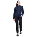 A woman stands wearing a navy blue Mountain Equipment Women’s Jorasses Lite Fleece Jacket, black trousers, and hiking shoes.