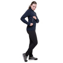 A person wearing a dark blue Women’s Jorasses Lite Fleece Jacket and black pants, opening a zippered pocket on the side of the garment.