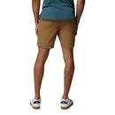 A person stands facing away, wearing a teal shirt and Columbia Mens ROC Tech Shorts in tan designed for stretch comfort, paired with white sneakers with blue accents. Their hands are relaxed by their sides against a plain white background.