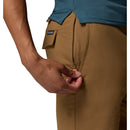 A person in Columbia Mens ROC Tech Shorts is zipping the side pocket of their brown, stretch-comfort shorts, which feature a visible brand tag above the pocket.