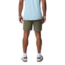 A person is standing facing away, wearing a light blue shirt, Columbia Mens ROC Tech Shorts in olive green, white socks, and white sneakers with blue accents against a plain white background.