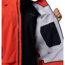 A person opens a bright red Columbia Mens Saudan Pro™ 3L Shell Jacket, revealing its light gray interior with a black zippered pocket and wearing a black Columbia shirt underneath, emphasizing its Omni-Tech Pro design for extreme conditions.
