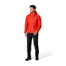 A man stands against a plain white background wearing the Rab Mens Microlight Alpine Hoody in bright red, paired with black pants and black boots.