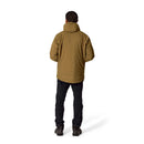 A person stands facing away, wearing a brown Rab Mens Microlight Shield Waterproof Down Jacket—featuring recycled down—paired with black pants and dark shoes against a plain white background.