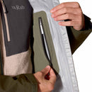 A person opens the inside zippered pocket of a Rab Men’s Namche GTX Waterproof Jacket, revealing part of its fleece inner layer and the Rab logo on a chest pocket—an ideal hiking shell engineered for performance in changing weather.