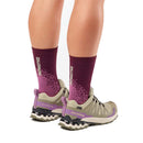 A person wearing maroon Salomon socks and beige Salomon Womens XA Pro 3D V9 GORE-TEX Trail Shoes with purple accents stands on a white background—ideal footwear for technical terrain.