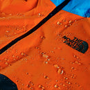Orange jacket with water droplets and 'The North Face' logo