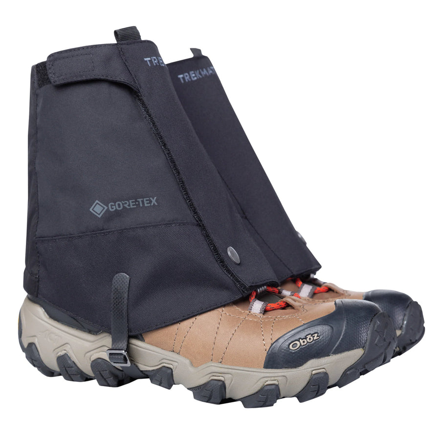 A pair of tan and black hiking shoes with thick soles are equipped with Trekmates Glenmore GORE-TEX Ankle Gaiters, which cover the ankles and uppers for enhanced trail protection and feature branded details.