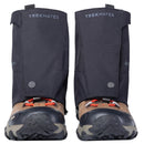 A pair of brown hiking boots equipped with black Trekmates Glenmore GORE-TEX Ankle Gaiters, featuring orange laces and rugged soles for enhanced trail protection, viewed from the front against a white background.