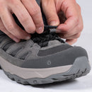 A close-up of hands tightening black elastic laces on a gray hiking shoe with a textured sole, preparing for wear—ideal for mountain walking and compatible with the Trekmates Cuillin GORE-TEX Gaiter for added protection.