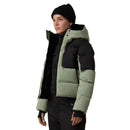 Person wearing a black and green puffer jacket on a light gray background