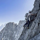 Person climbing a rocky mountain with a clear blue sky