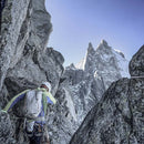 Person climbing a rocky mountain with snow-capped peaks in the background