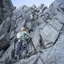 Person climbing a rocky mountain face with gear