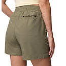 A person is shown from behind wearing Columbia Womens Cedar Crest Hiking Shorts in olive green, featuring an elastic waistband and a back pocket, set against a plain white background.
