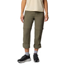 A person stands facing forward in Columbia Womens Leslie Falls Hiking Convertible Trousers, a beige short-sleeve shirt, gray socks, and black athletic shoes against a plain white background. The face is not visible.