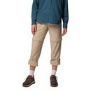 A person wears Columbia Womens Leslie Falls Hiking Convertible Trousers with Omni-Shield, beige with zippers above the knees and rolled cuffs, plus a teal button-up shirt, white socks, and brown sneakers. The persons head is not visible.
