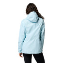 A person with long, wavy hair is shown from the back, wearing a light blue Columbia Womens Pouring Adventure III Waterproof Hiking Jacket and black pants against a plain white background.