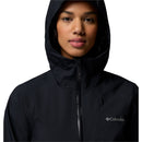 A woman wearing a Columbia Womens Trailborne 2.5L Waterproof Shell Jacket in black, hood up, faces forward with a neutral expression against a plain white background.