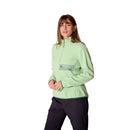 A woman wearing the Rab Womens Ramshaw Pull-On Fleece in light green, featuring a recycled fleece material, quarter-zip design, and a front zip pocket, paired with black pants, stands against a plain white background.