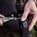 Person using a multi-tool to adjust a camera tripod outdoors