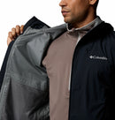 Man wearing a Columbia jacket with a close-up of the brand logo and the omni-tech waterproofing inside.